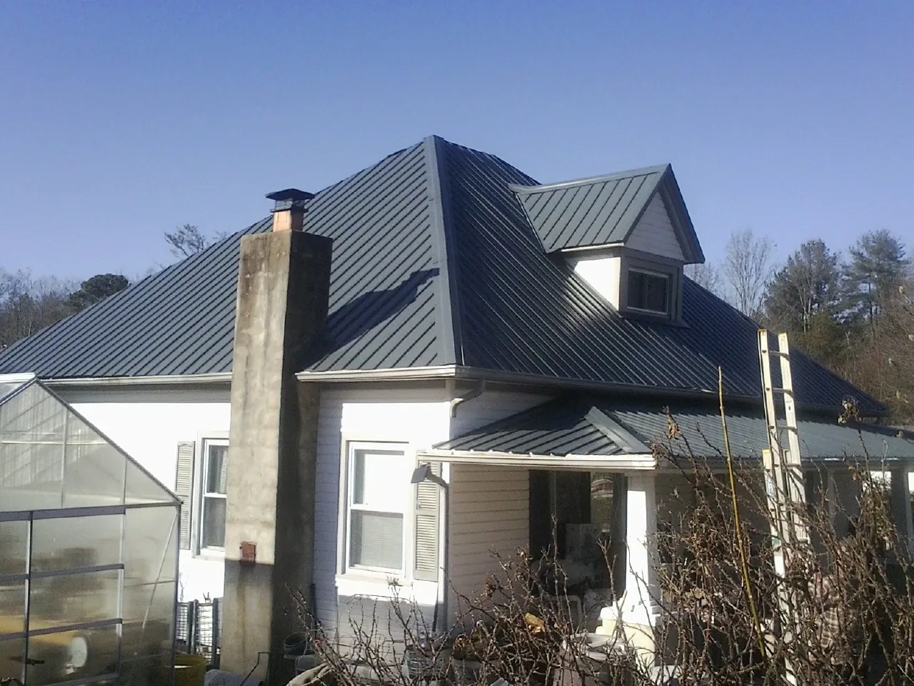 Dark blue standing seam metal roof on a white farmhouse with dormer — Slate & Tile Roof Repair by Roofing Brothers in Orion