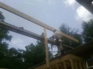 Carpenter setting a ridge beam over a new addition frame — Ice Dam Removal by Roofing Brothers in Orion