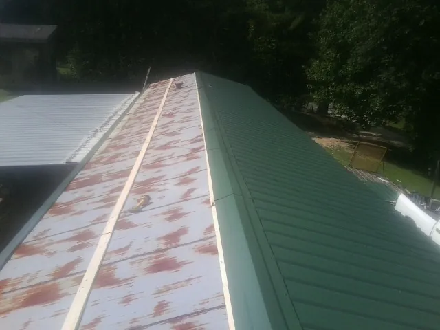 Old rusted panels beside newly installed green metal roofing — Wind Damage Roof Repair by Roofing Brothers in Orion