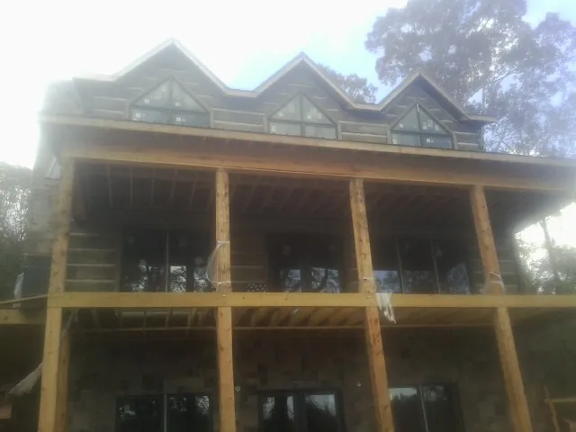 Dormers and porch framing on a large log home under construction — Roof Coating work by our crew in Orion