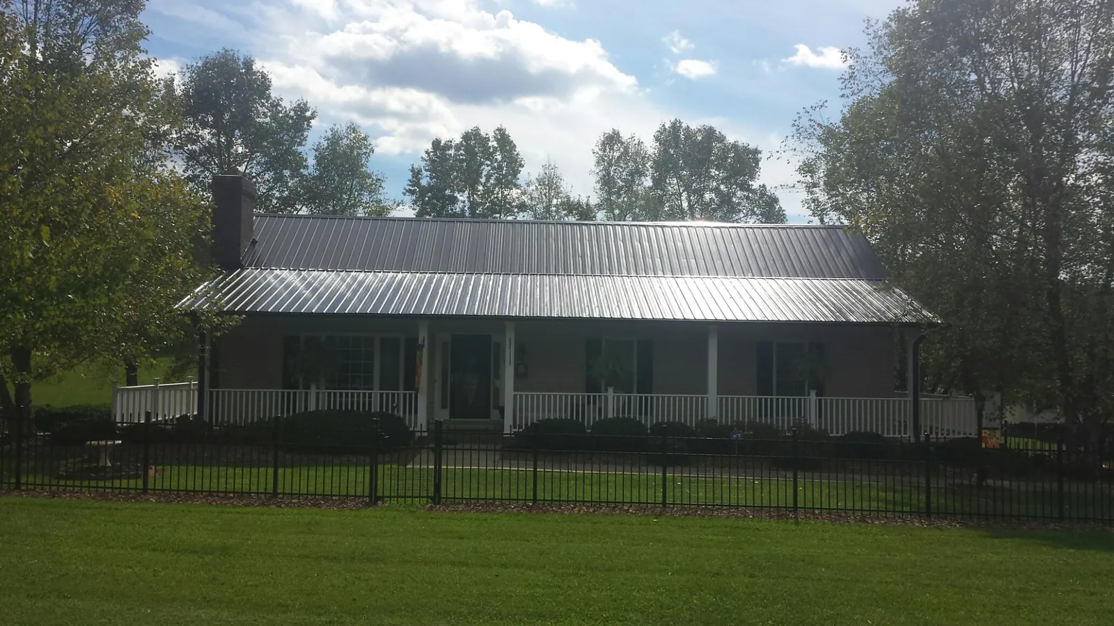 Gray metal roof on a brick ranch with a full width front porch — Gutter Guard Installation work by our crew in Orion