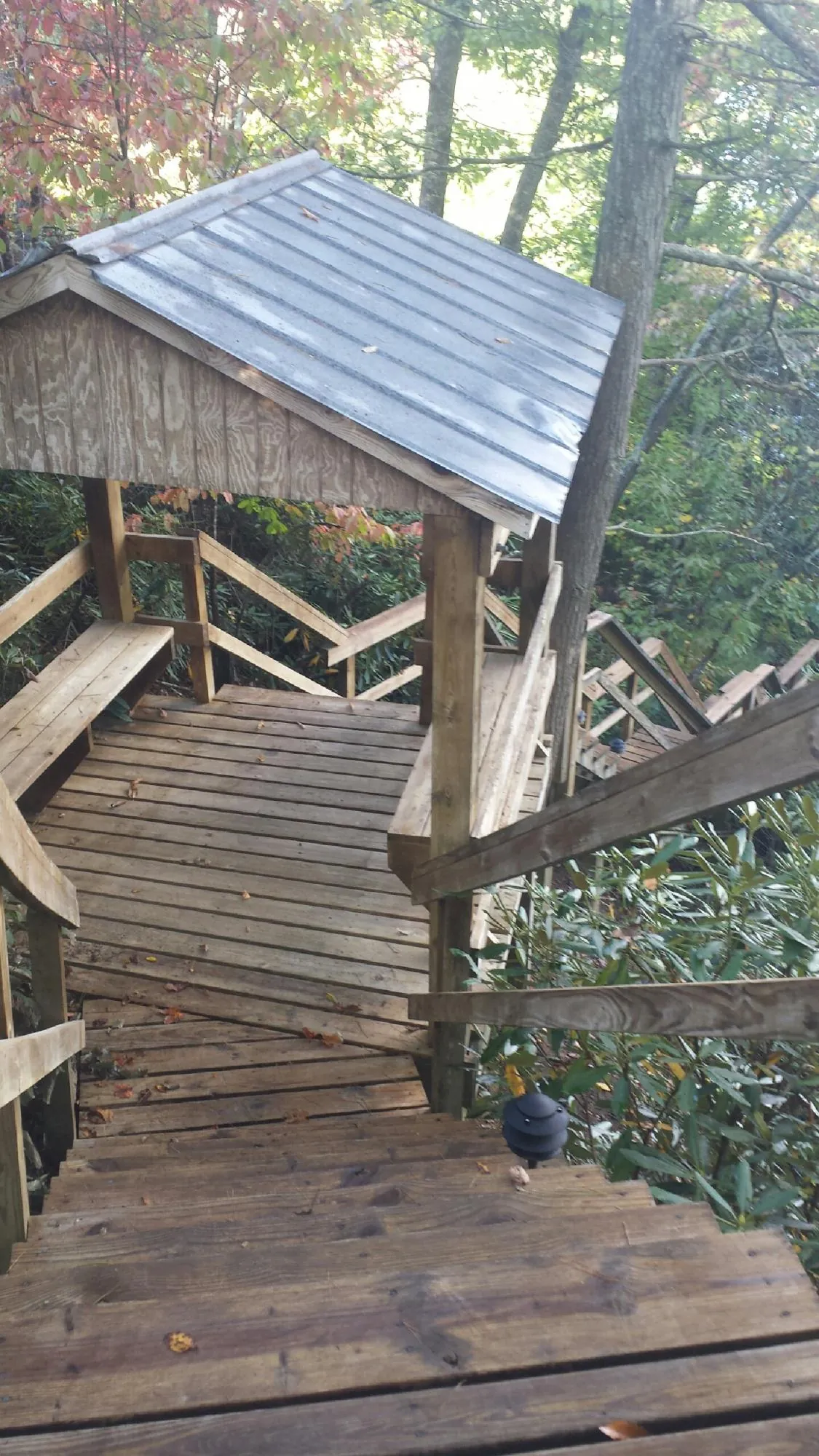 Metal roofed shelter over wooden steps on a wooded walkway — Skylight Repair & Installation work by our crew in Orion