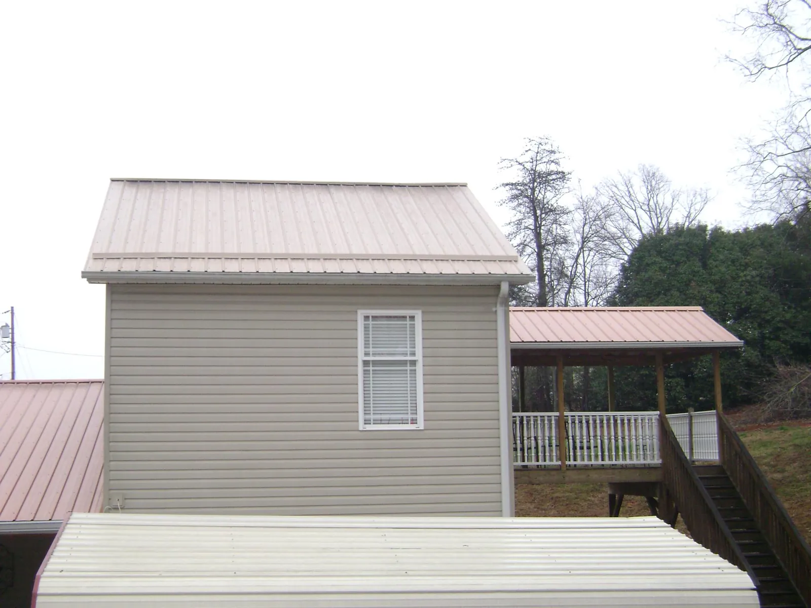 Tan metal roofs on a two story addition and attached porch, from a Roof Replacement job in Orion