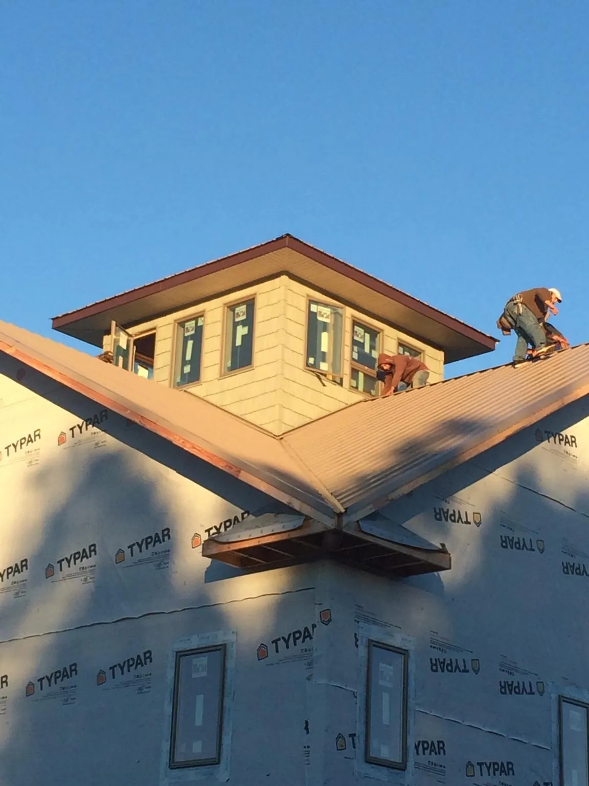 Roofers working around a rooftop cupola on a new metal roof at sunset — Roof Waterproofing in Orion by Roofing Brothers